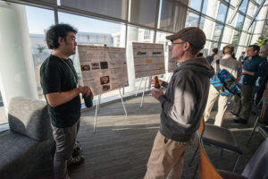 Attendees standing near posters on easels and mingling at the CNS Research Review October 22, 2014 Poster Session