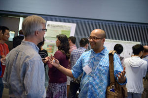 Attendees standing near posters on easels and mingling at the CNS Research Review October 22, 2014 Poster Session