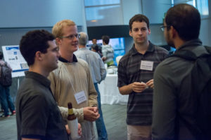 Attendees standing near posters on easels and mingling at the CNS Research Review October 22, 2014 Poster Session
