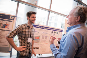 Attendees standing near posters on easels and mingling at the CNS Research Review 2017 Poster Session