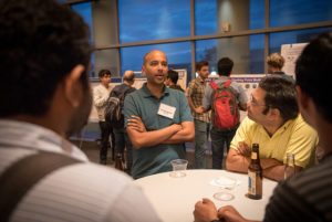 Attendees standing near posters on easels and mingling at the CNS Research Review 2017 Poster Session